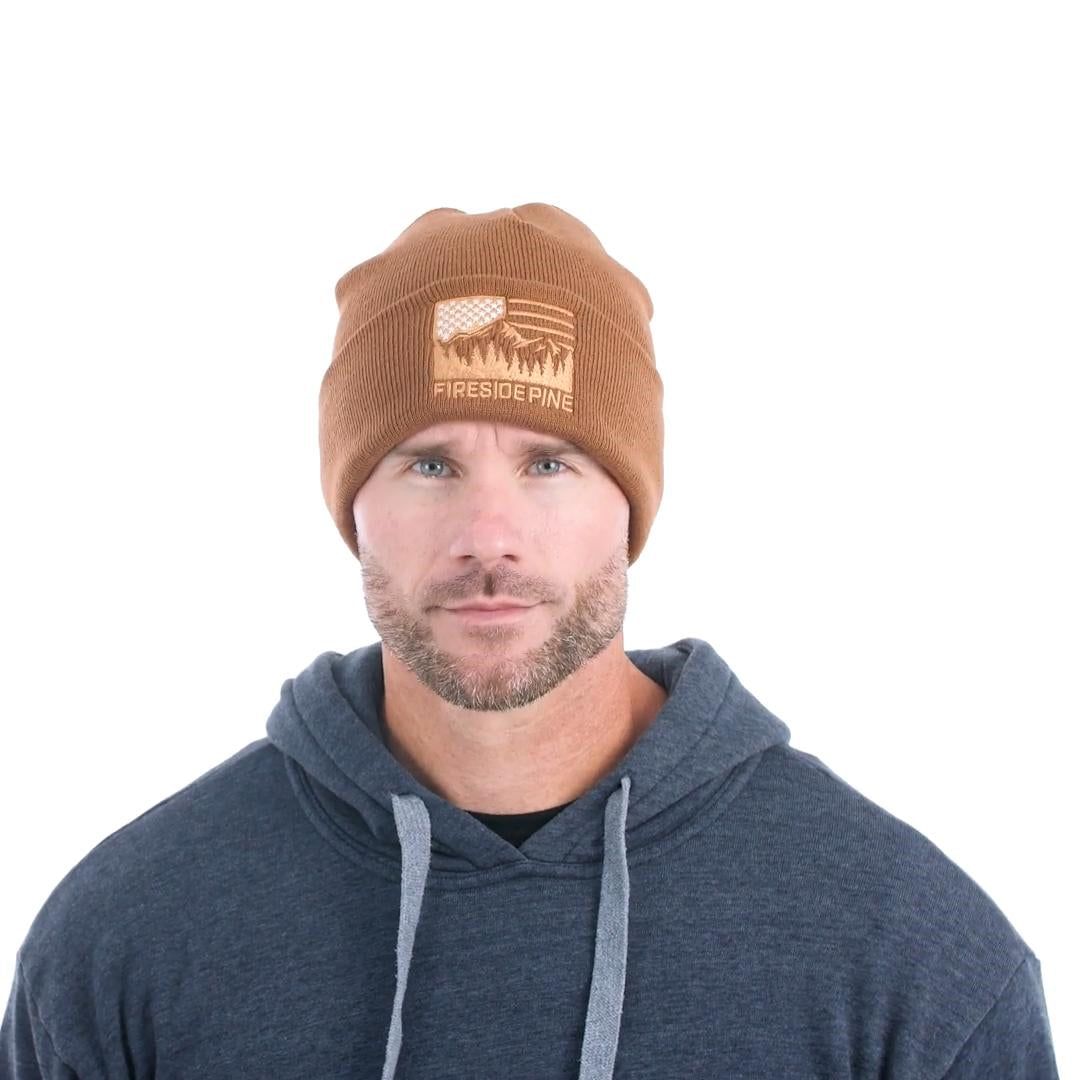 Made in USA. 100% Acrylic Knit beanie. Measuring approximately 12 inches long. Brown colored beanie featuring the Fireside Pine American Flag Mountain logo embroidered on the front. Model Fit Video.